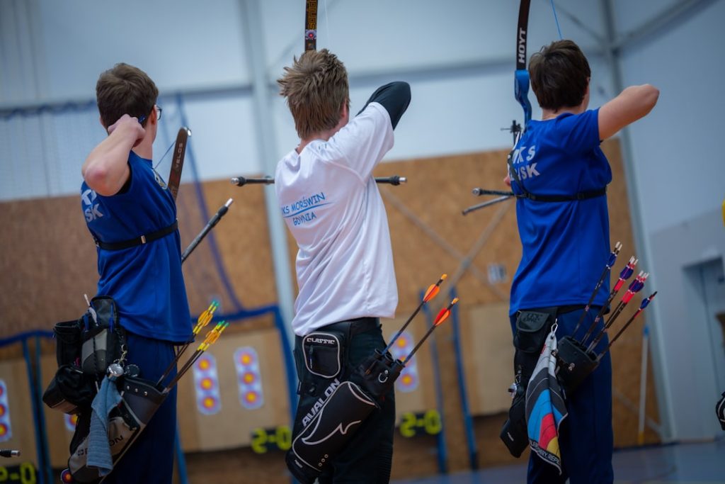 three-archers-aiming-at-targets-in-an-indoor-range-ybw7k9gbs58